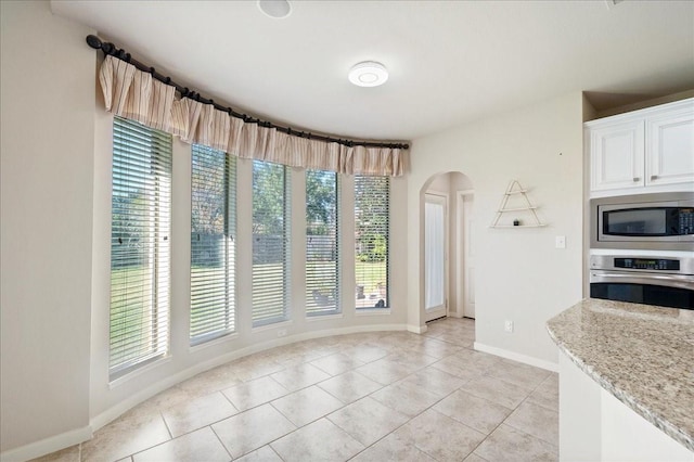 tiled dining room featuring light stone countertops, white cabinetry, and plenty of natural light