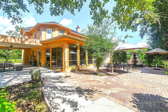 rear view of property with fence, a sunroom, stucco siding, a chimney, and a patio area