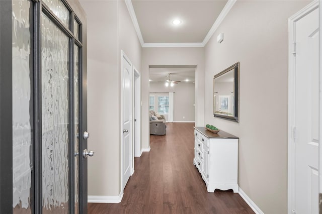 hall with dark wood-type flooring, baseboards, and ornamental molding