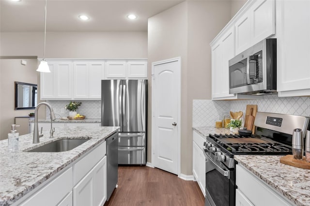 kitchen with sink, hanging light fixtures, white cabinets, and appliances with stainless steel finishes