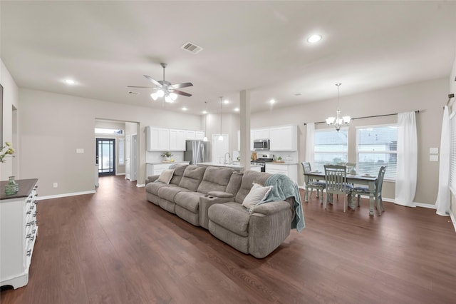 living room featuring ceiling fan with notable chandelier and dark hardwood / wood-style flooring