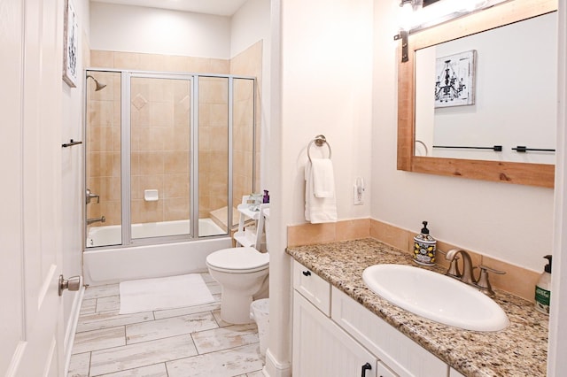 full bathroom with vanity, enclosed tub / shower combo, and toilet