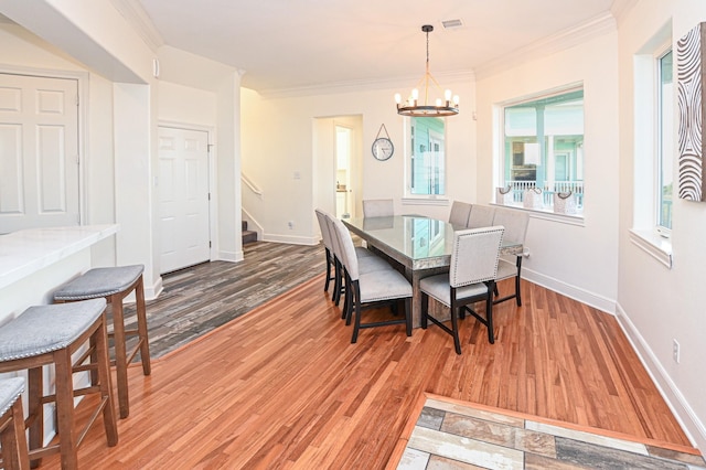 dining space with crown molding, wood-type flooring, and a notable chandelier