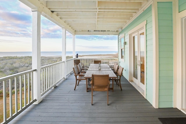 wooden deck with french doors, a water view, and a view of the beach