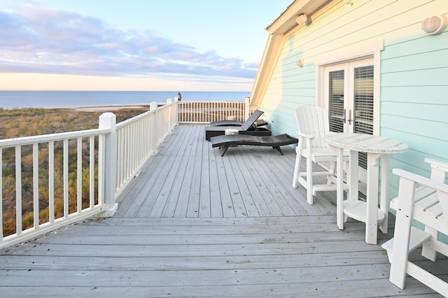 deck at dusk with a water view and french doors