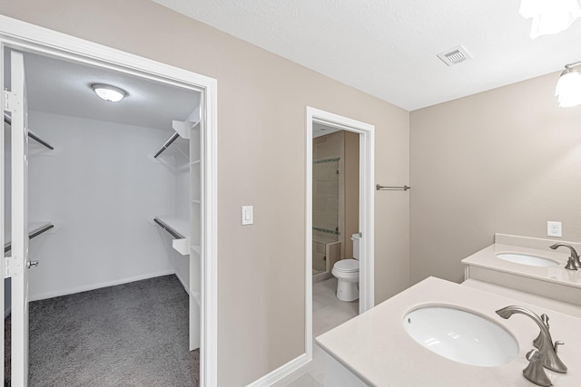 bathroom featuring vanity, a shower, a textured ceiling, and toilet