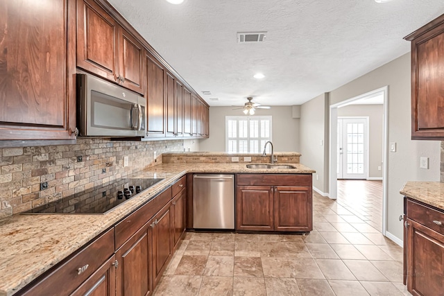 kitchen featuring sink, stainless steel appliances, tasteful backsplash, light stone countertops, and kitchen peninsula