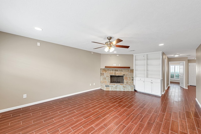 unfurnished living room featuring ceiling fan, a textured ceiling, a fireplace, and wood-type flooring