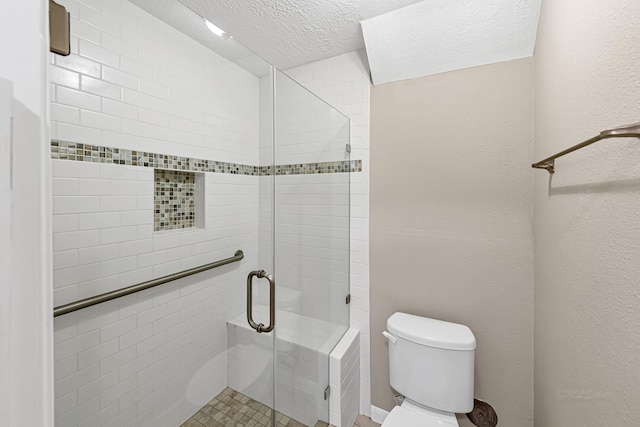 bathroom with toilet, a shower with shower door, and a textured ceiling