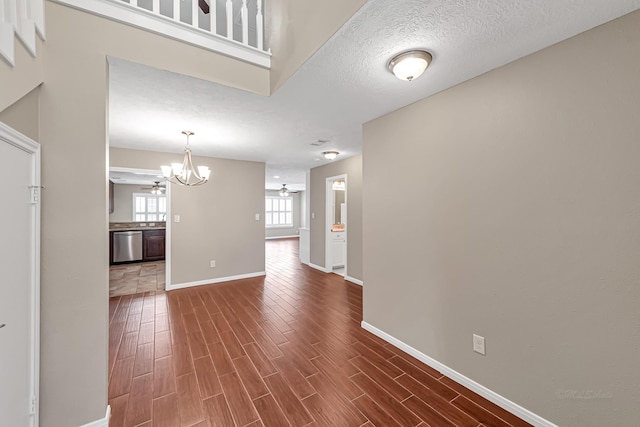 interior space with dark wood-type flooring, ceiling fan with notable chandelier, and a textured ceiling