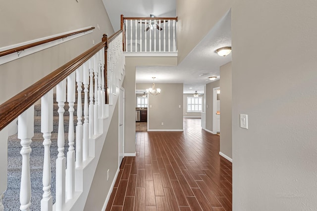 staircase featuring ceiling fan with notable chandelier