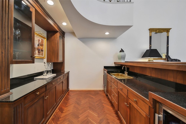 kitchen with dark countertops, glass insert cabinets, a sink, and recessed lighting