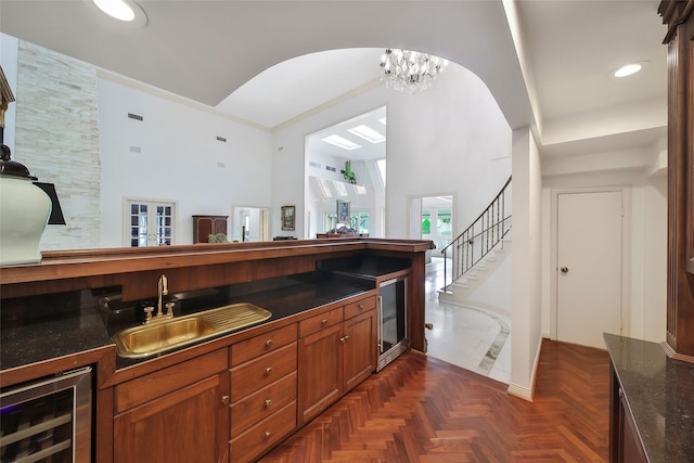 bar with wine cooler, an inviting chandelier, stairs, a sink, and recessed lighting