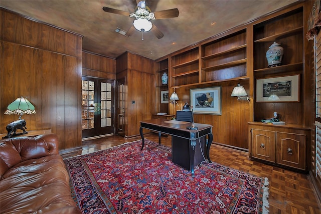 home office with ceiling fan, french doors, wood walls, and visible vents