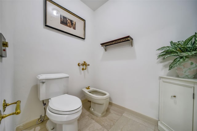 bathroom with toilet, marble finish floor, and baseboards