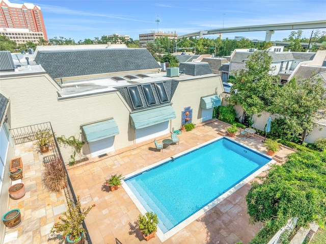 rear view of property featuring a patio area, cooling unit, a fenced in pool, and fence