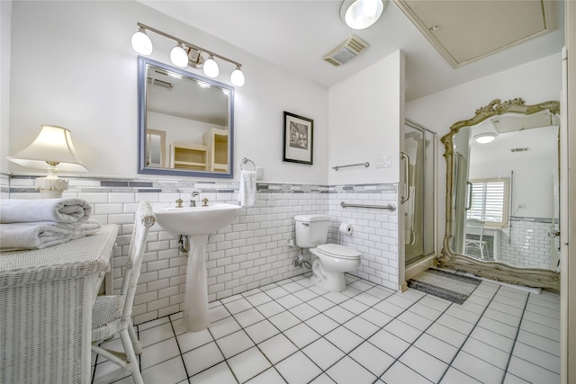 full bathroom with wainscoting, tile walls, toilet, and tile patterned floors