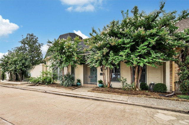 view of property hidden behind natural elements with brick siding