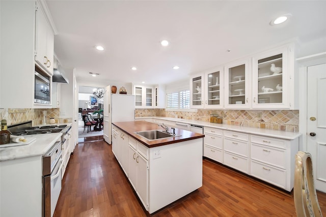 kitchen featuring a center island with sink, stainless steel microwave, dark wood-style flooring, and a sink