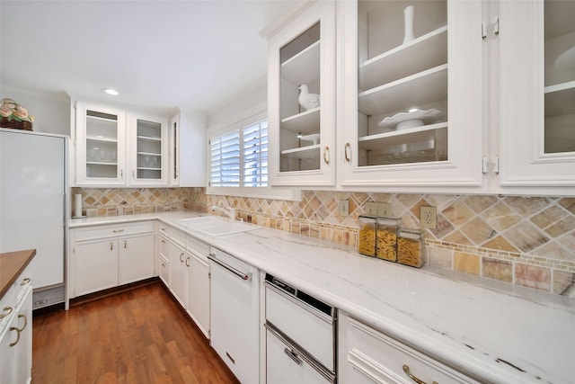 kitchen featuring light stone counters, tasteful backsplash, dark wood-type flooring, white cabinets, and a sink