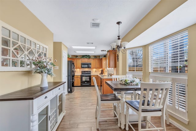 dining space featuring visible vents, light wood finished floors, and a chandelier