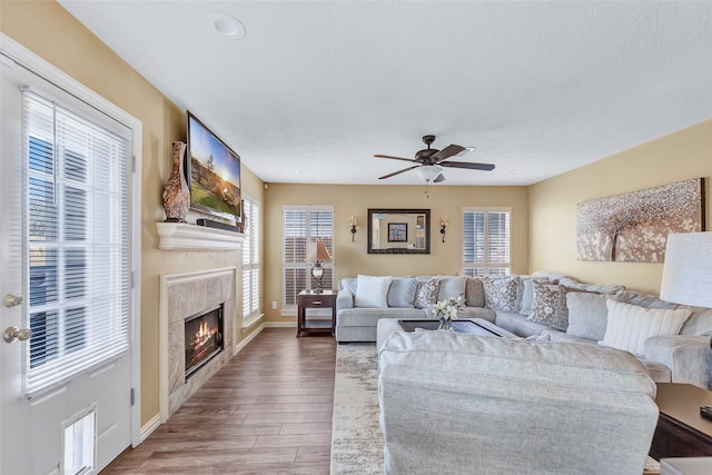 living area with baseboards, a ceiling fan, wood finished floors, and a high end fireplace