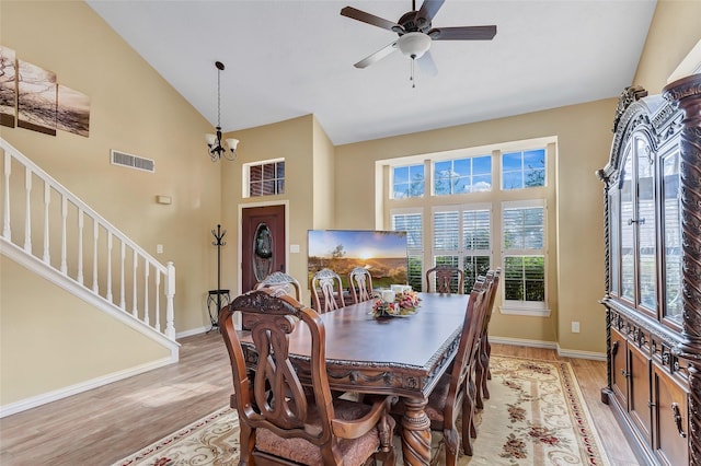 dining space with light wood-type flooring, stairway, high vaulted ceiling, and visible vents