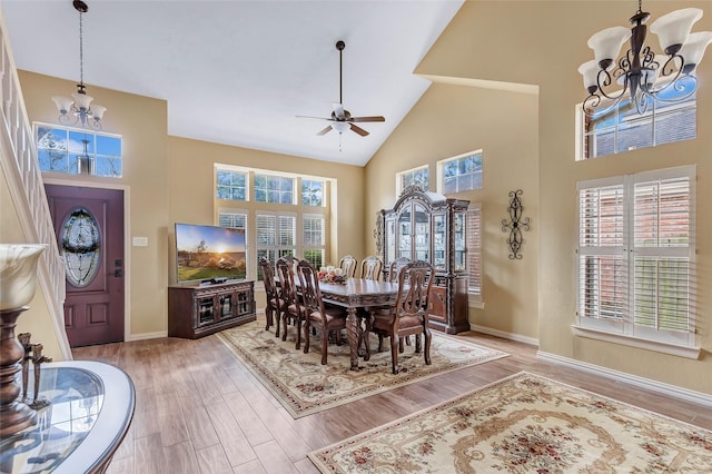 dining area with baseboards, light wood-style flooring, high vaulted ceiling, and a healthy amount of sunlight