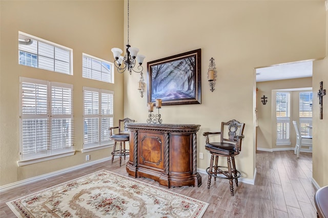 interior space with a high ceiling, a notable chandelier, wood finished floors, and baseboards