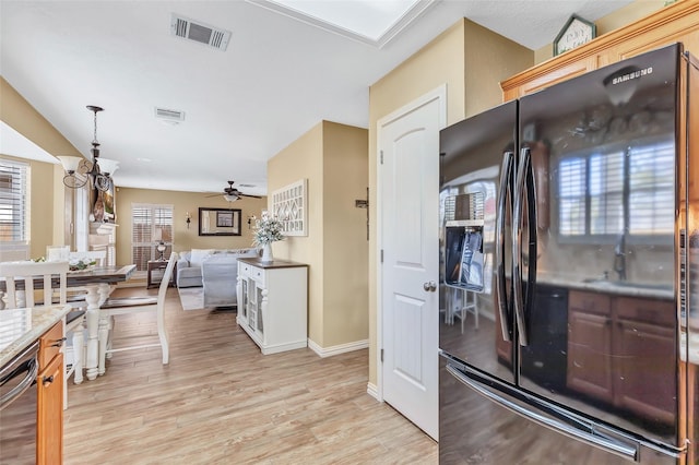 kitchen featuring light wood finished floors, visible vents, open floor plan, dishwasher, and black refrigerator with ice dispenser