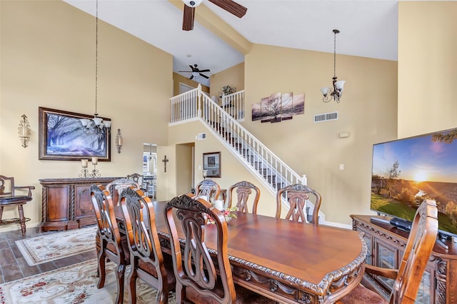 dining room featuring visible vents, stairs, ceiling fan with notable chandelier, wood finished floors, and high vaulted ceiling