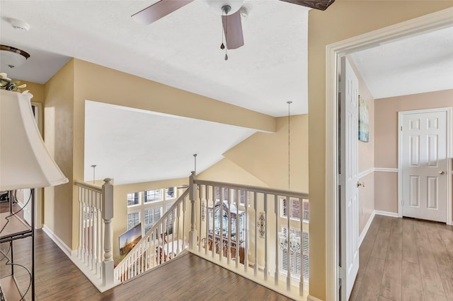 corridor with lofted ceiling with beams, an upstairs landing, and wood finished floors