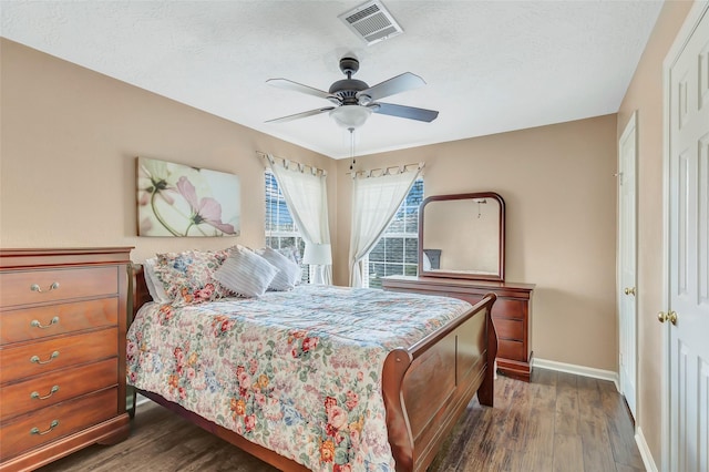 bedroom with a textured ceiling, dark wood-style floors, visible vents, and baseboards