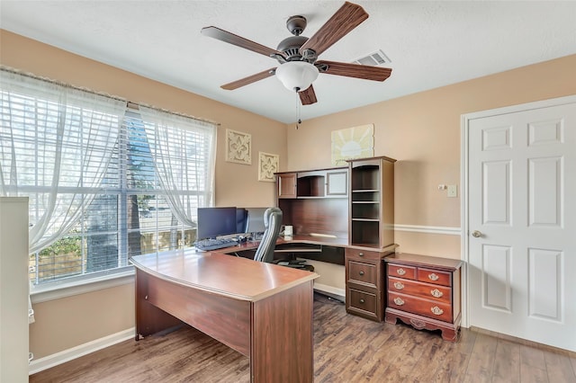 home office with visible vents, baseboards, wood finished floors, and a ceiling fan