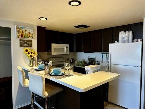 kitchen with white appliances, a kitchen bar, and kitchen peninsula