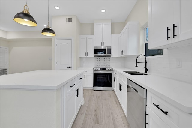 kitchen with white cabinetry, stainless steel appliances, a center island, and sink