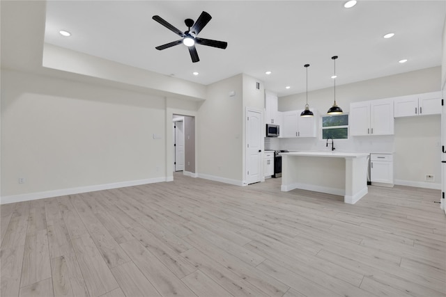 unfurnished living room with sink, ceiling fan, and light wood-type flooring