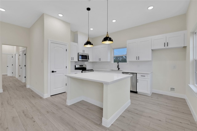 kitchen featuring white cabinetry, stainless steel appliances, a center island, and sink