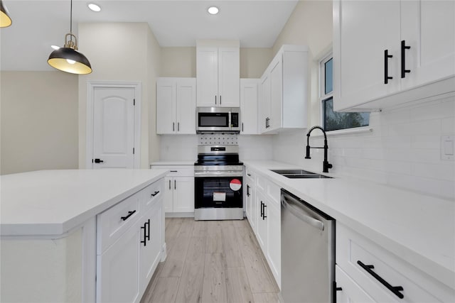 kitchen with sink, hanging light fixtures, stainless steel appliances, decorative backsplash, and white cabinets