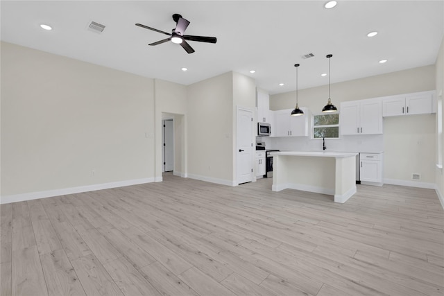 kitchen with pendant lighting, appliances with stainless steel finishes, a kitchen island, and white cabinets