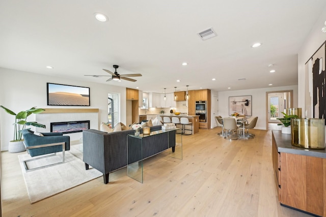 living room with ceiling fan and light wood-type flooring