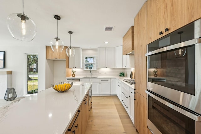 kitchen with sink, appliances with stainless steel finishes, hanging light fixtures, tasteful backsplash, and white cabinets