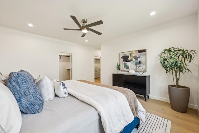 bedroom with ceiling fan, a walk in closet, and light wood-type flooring