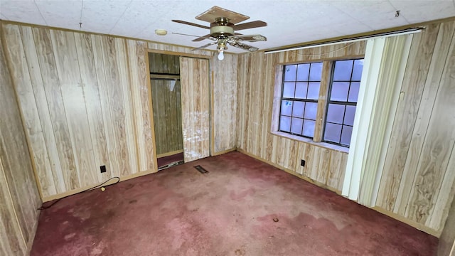 unfurnished bedroom featuring a closet, wood walls, ceiling fan, and carpet