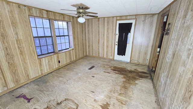 unfurnished room with ceiling fan and wooden walls