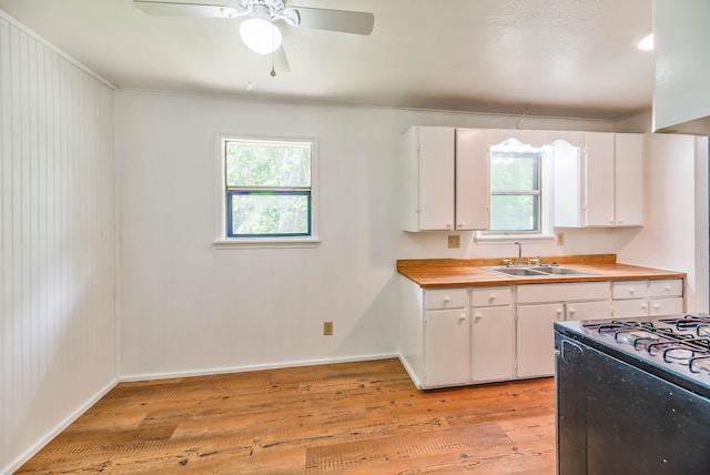 kitchen featuring sink, wooden counters, light wood-type flooring, white cabinets, and stove