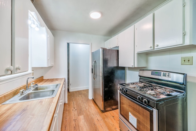 kitchen featuring sink, light wood-type flooring, appliances with stainless steel finishes, decorative backsplash, and white cabinets