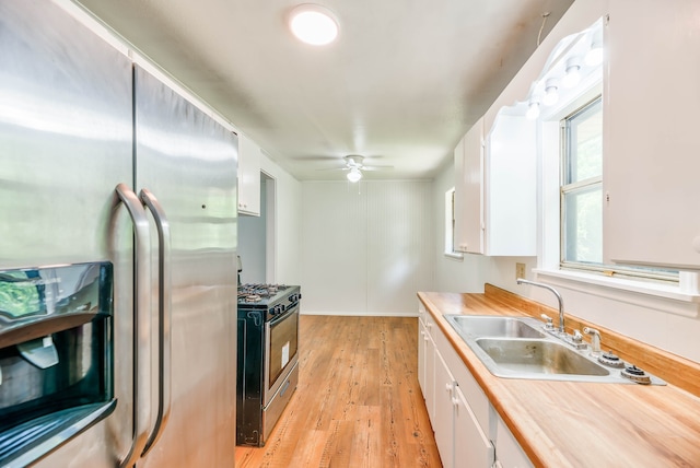 kitchen with white cabinetry, stainless steel appliances, sink, and light wood-type flooring