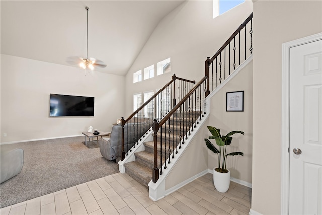 staircase with carpet floors, high vaulted ceiling, and ceiling fan