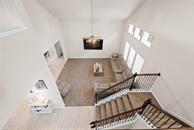 stairway featuring ceiling fan and a high ceiling